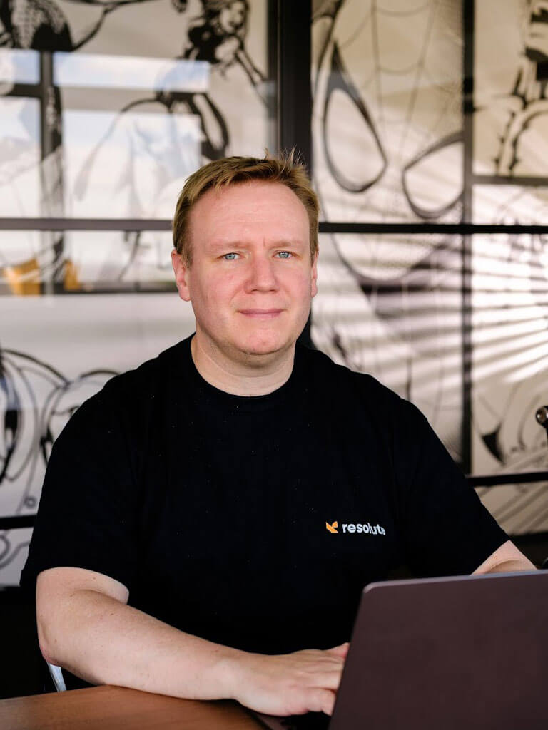 Resolute Cyber team member working on a laptop, seated in a modern office with artistic decor in the background.